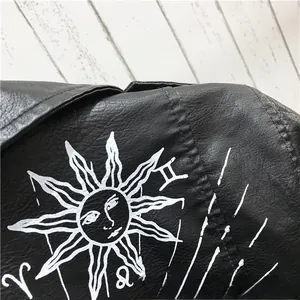 Détail d'une veste en similicuir noir avec imprimés de soleil et signes du zodiaque