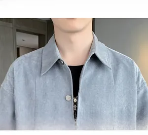 Detail of greyish-blue corduroy jacket with notch lapel and branded metal button