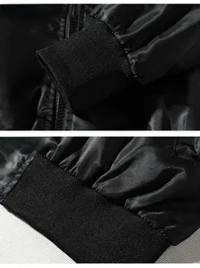 Detailed macro view of black satin bomber jacket showing ribbed cuffs and zipper texture