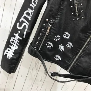 Détail de la veste de moto en PU noir avec imprimés yeux et rivets argentés