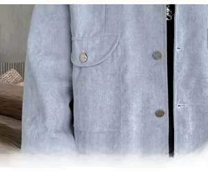 Detail shot of blue corduroy jacket showing large flap pocket and branded button
