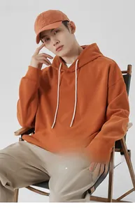 Détail d'un sweat à capuche orange en coton épais avec cordons blancs et casquette assortie