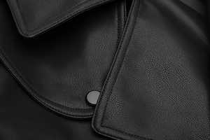 Close-up of black faux leather jacket featuring fine grain texture and matte round button
