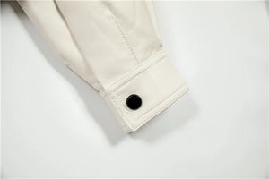 Detailed macro view of the sleeve cuff on a cream leather jacket with a black snap button