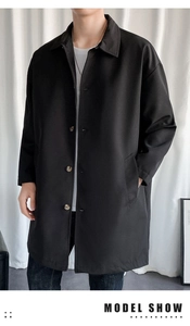 Detail of single-breasted black trench coat with amber buttons and slant pockets