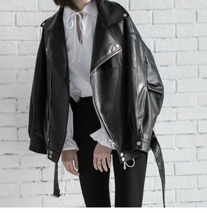 Close-up of black oversized faux leather biker jacket with silver buckles and waist belt