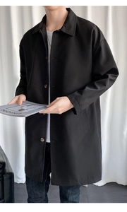 Detailed view of single-breasted black trench coat with amber buttons and lapel collar