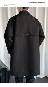 Detail of windbreak flap with elegant gold script embroidery on black men's trench coat