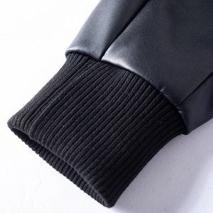 Macro shot of black leather jacket sleeves with ribbed knit cuffs and fine texture
