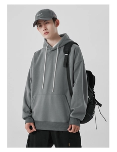 Détail d'un sweat à capuche en coton gris épais avec broderie New York et cordon blanc