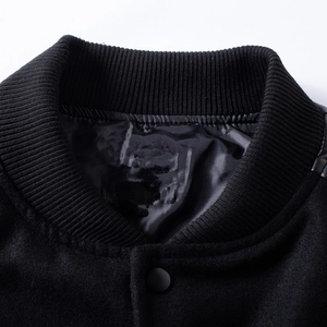 Detail of classic ribbed knit collar on black wool varsity jacket with leather patchwork