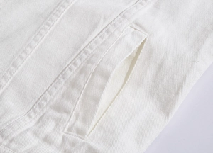 Close-up of a white denim vest showing heavy twill texture and neat welt pocket stitching