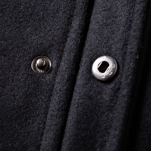 Detailed macro view of black wool fabric texture and durable metal snap button closure