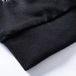 Detailed close-up of wool fabric and ribbed knit cuffs on a black varsity jacket