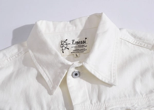 Close-up of white denim vest collar with brand label and silver metal button detail