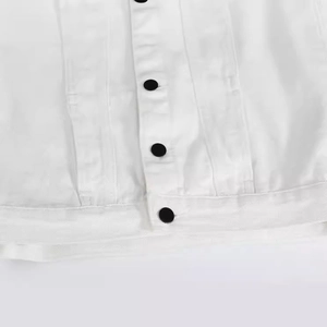 Close-up of white denim vest featuring black contrast buttons and heavy cotton twill texture
