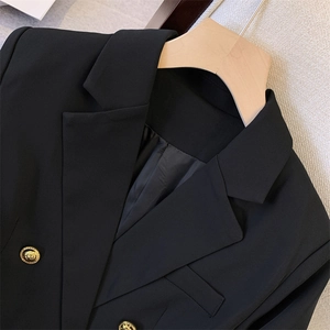 Detail of black blazer texture featuring ornate gold embossed lion head buttons