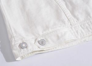 Detailed macro view of white denim vest hem featuring polished silver metal buckle