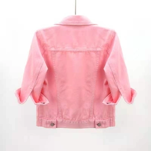 Detail view of the back seams and metal hem buckles on a pink cropped denim jacket