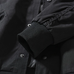 Detail of ribbed knit cuff and metallic snap button on black MA1 flight jacket