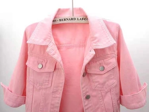 Detail shot of a pink denim jacket with classic collar and flap chest pockets