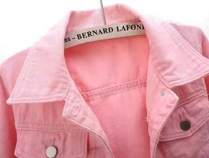 Close-up of pink denim jacket featuring silver metal buttons and a classic lapel collar