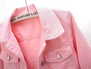 Detail of pink denim jacket collar and silver metal buttons on a wooden hanger