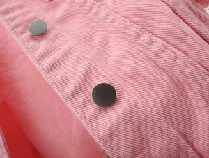 Detailed macro view of pink corduroy jacket showing double-breasted black buttons and texture