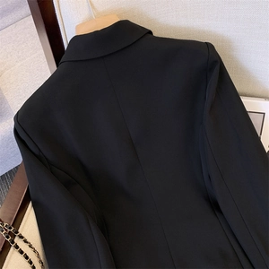 Detailed view of black blazer shoulder tailoring and premium woven fabric texture