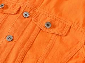 Detailed close-up of orange denim jacket featuring flap pocket and silver metal buttons