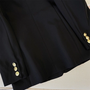 Close-up of golden embossed buttons and premium woven fabric on black blazer
