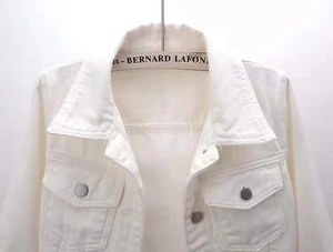 Detailed view of white denim jacket lapel and silver buttons with breast pockets