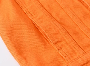 Macro shot of bright orange denim fabric featuring twill weave and tonal stitching detail