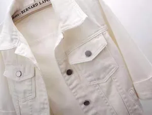 Detail of white cotton denim jacket featuring chest flap pockets and silver metal buttons