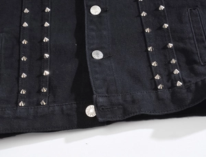Detail of black denim vest featuring silver metal studs and branded metal buttons