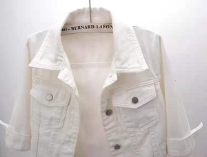 Detailed macro view of white denim jacket with metal buttons and chest pockets