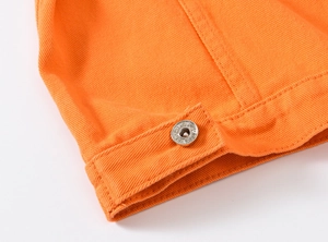Detail of bright orange denim jacket featuring a silver metal button and neat stitching