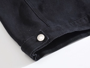 Close-up of black denim fabric with silver metal buttons engraved with JEANS