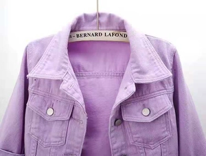 Detail of purple denim jacket collar and chest pockets with metallic buttons