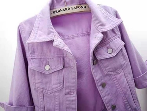 Detailed close-up of light purple denim jacket collar with pockets and metal buttons