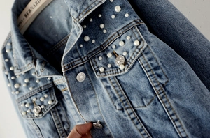 Detailed view of light blue denim jacket featuring exquisite faux pearls and rhinestones