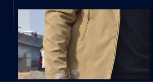 Detail view of khaki tactical jacket showing adjustable velcro cuffs and side zipper pockets