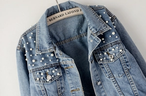Detailed view of light blue denim jacket featuring elegant white pearl bead decorations