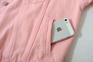 Detailed macro view of side pocket on pink denim jacket showing storage depth for smartphone