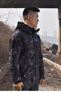 Detail view of camouflage tactical softshell jacket featuring velcro arm patch and pockets