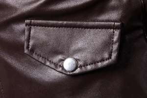 Close-up of dark brown leather jacket pocket with fine stitching and silver metal button
