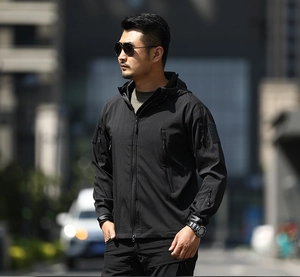Men's black tactical softshell jacket featuring multiple zipper pockets and arm velcro patches