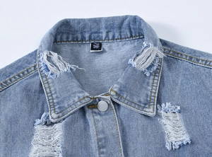 Gros plan détaillé du gilet en jean bleu clair avec trous usés et bouton en métal