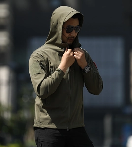 Detail of army green tactical softshell jacket with zipper pockets and velcro patch
