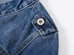 Détails de la texture du denim bleu foncé et du bouton métallique vintage sur la veste